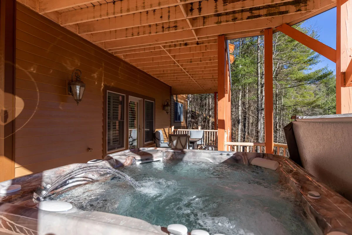 A tranquil scene featuring a hot tub on a wooden deck, surrounded by lush trees. The inviting setup is ideal for relaxing after active days, with the natural beauty of the outdoors creating a peaceful retreat for families to unwind and reconnect.